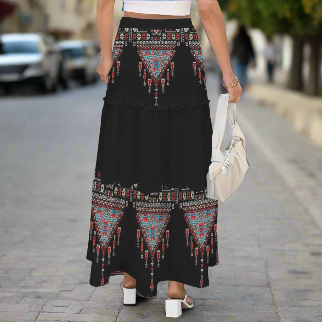 Person wearing a black Palestinian tatreez print embroidered skirt with geometric patterns