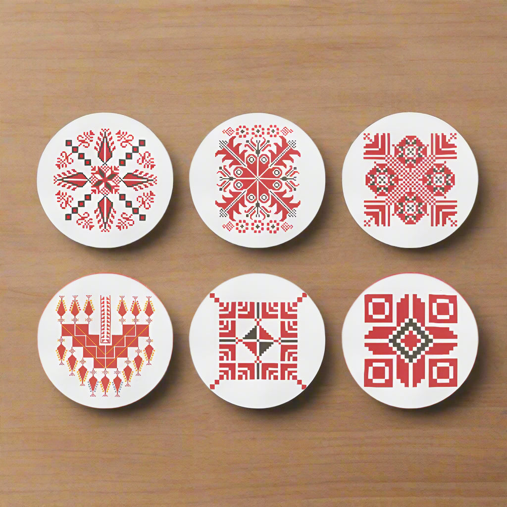 Set of six coasters with red geometric tatreez patterns on white background