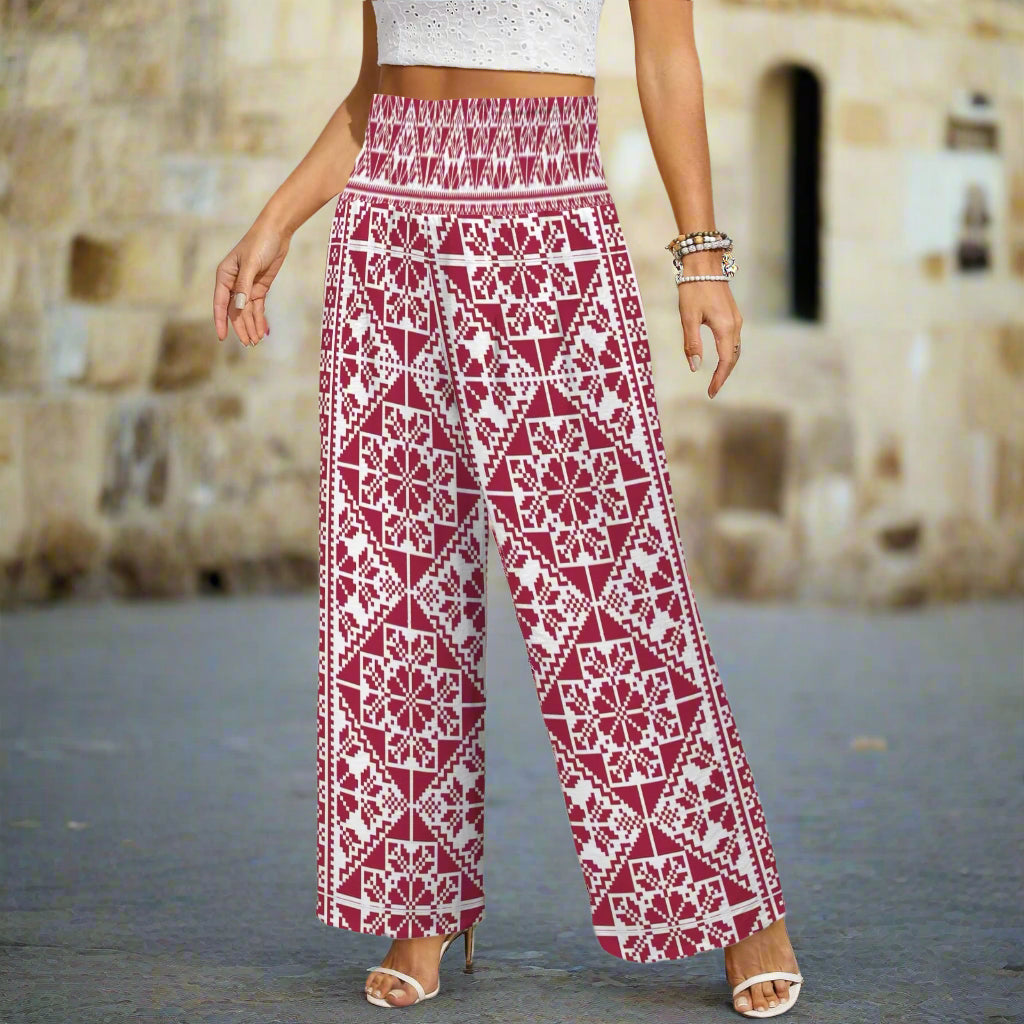 Person wearing a pair of wide-leg pants with a red and white tatreez print embroidered print palestinian geometric pattern