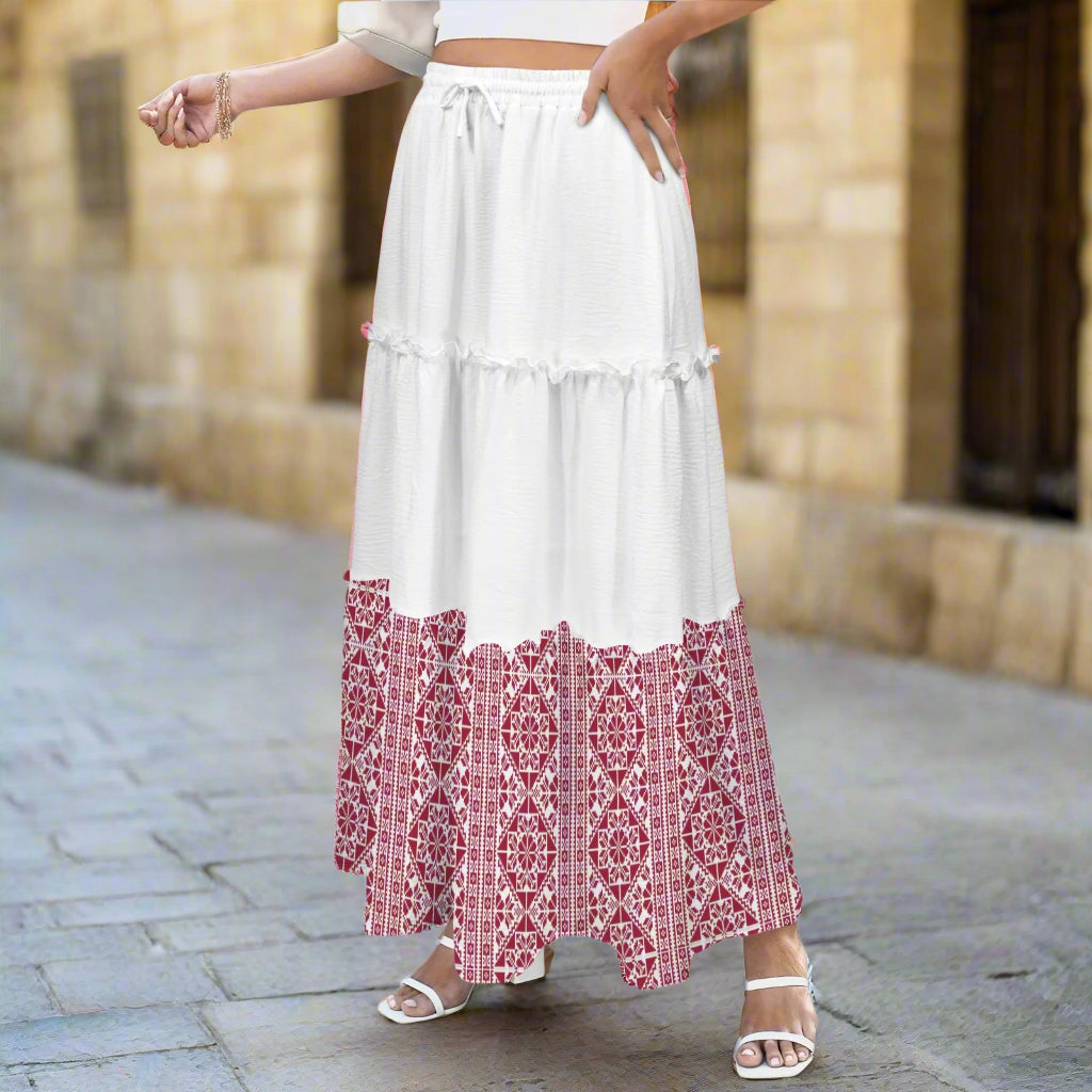 Person wearing a white and red tatreez palestinian patterned skirt