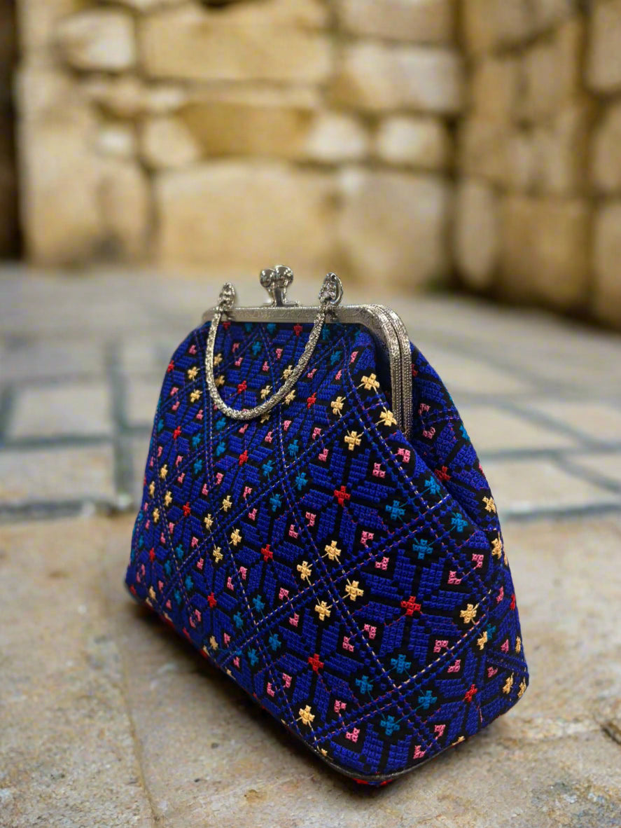 Blue tatreez embroidered handbag on a wooden surface