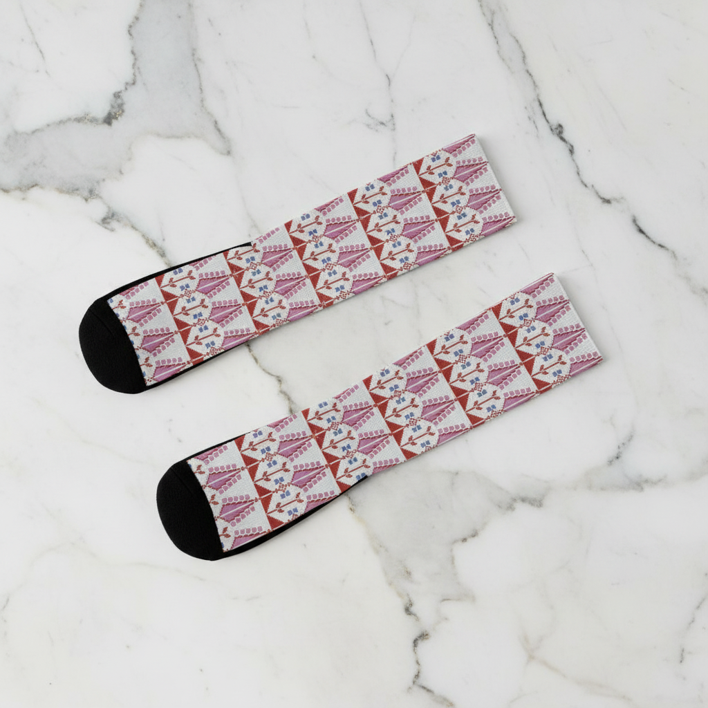Two socks with a palestinian tatreez pattern print on a marble surface