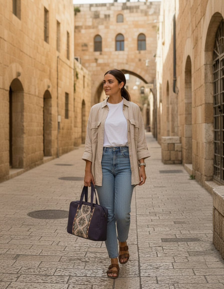 Woman walking down with tatreez embroidered palestinian tote bag street in an old town with a beige jacket and blue jeans iin jerusalem