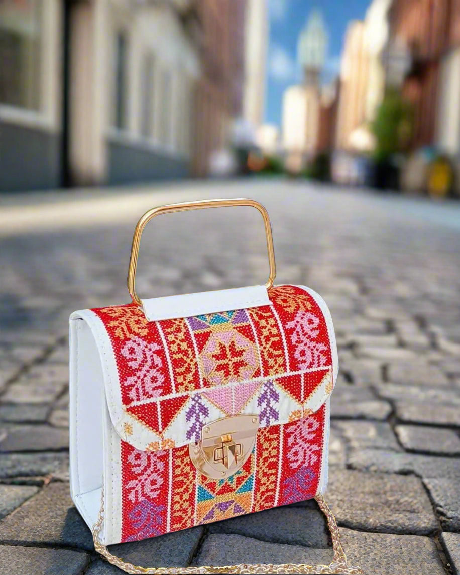 Colorful embroidered embroidered tatreez handbag with a gold chain on a blurred indoor background