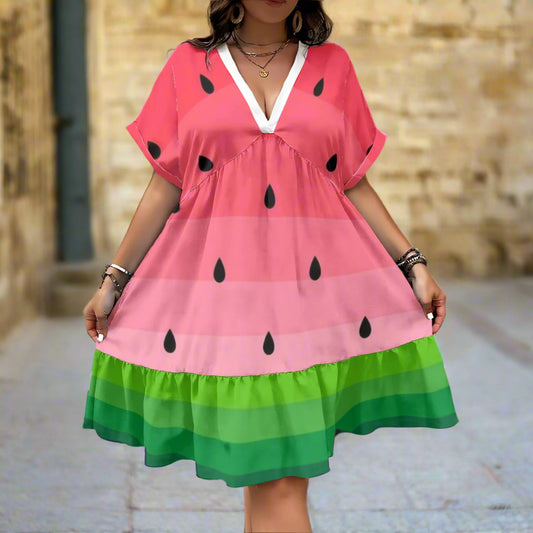 Person wearing a watermelon-themed dress against a textured wall.
